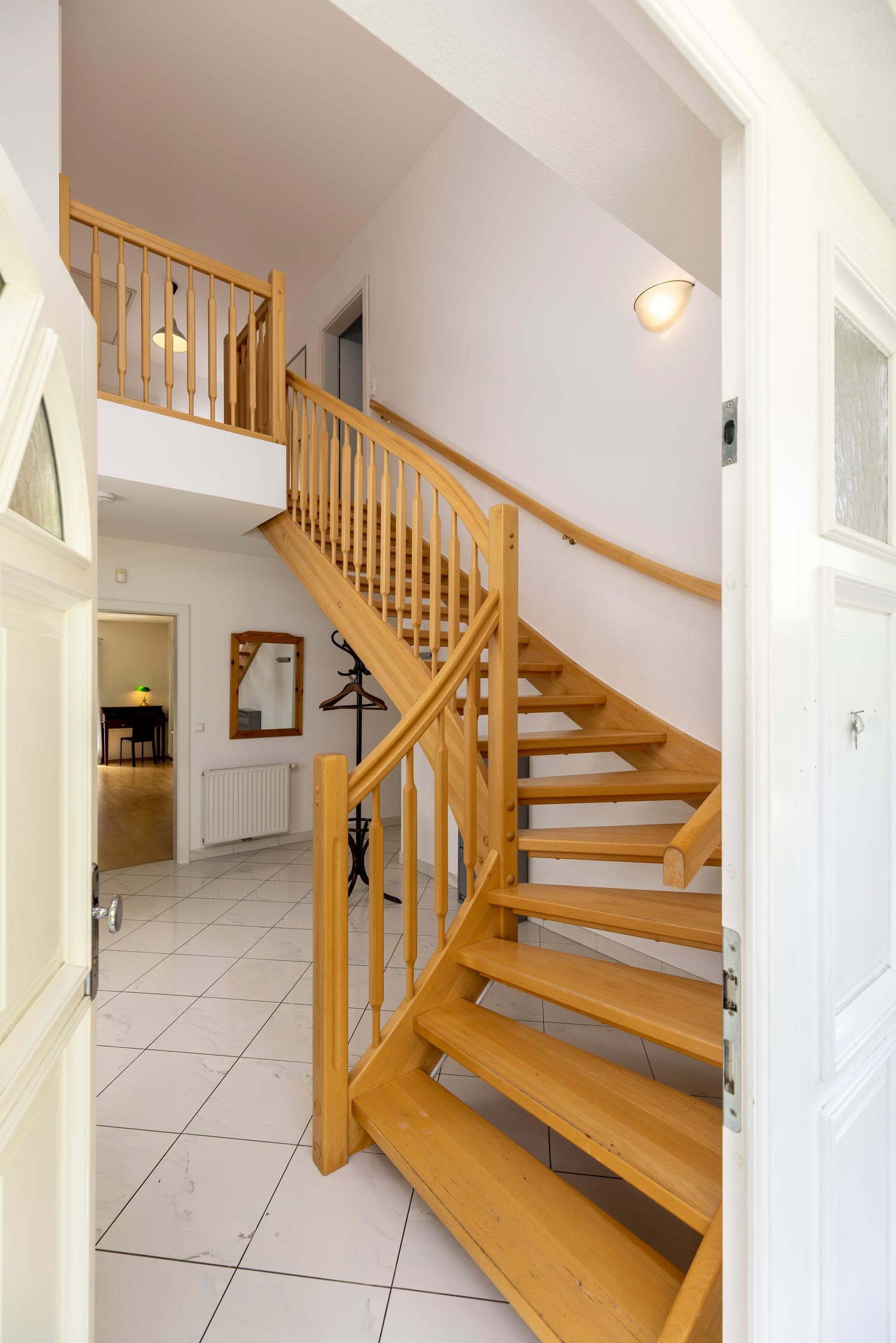 Helle Holztreppe mit geschwungenem Geländer im Eingangsbereich