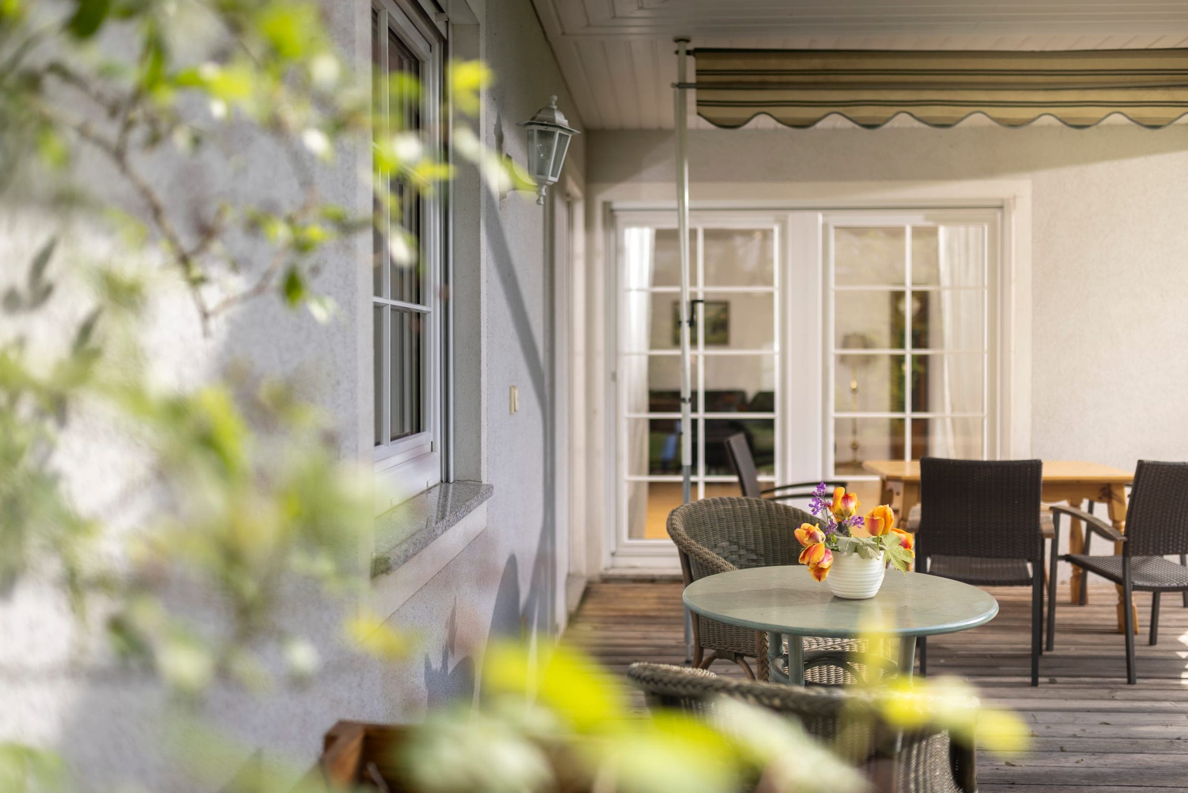 Terrasse mit Markise und Sitzgelegenheit, Blick durch Blätter